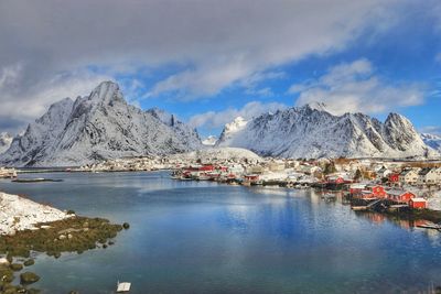 Town by lake against snowcapped mountains during winter