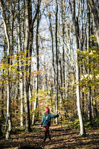 Full length rear view of woman walking by trees in forest