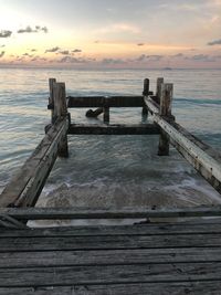 Wooden pier over sea against sky during sunset