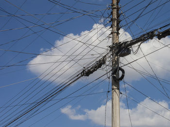 Low angle view of electricity pylon against blue sky