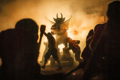 People pushing sculpture during festival at night