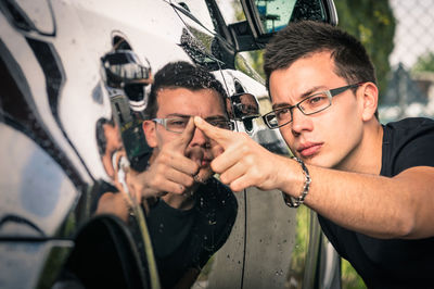 Portrait of young man holding camera in car