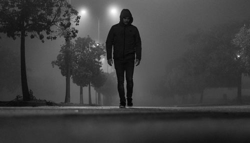 Man standing on street against illuminated city at night