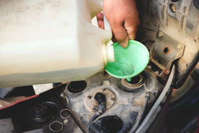 Cropped hand pouring petrol in motor scooter