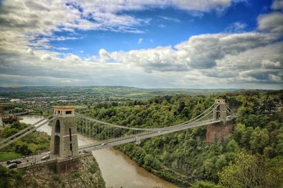 Bridge over river in city against cloudy sky