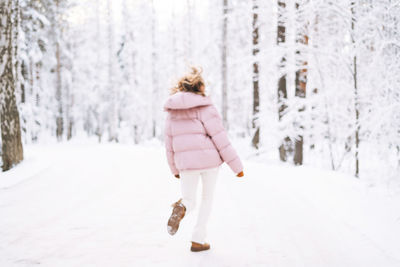 Rear view of woman walking on snow covered field