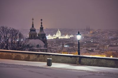 View of illuminated street against snowy city at night. cityscape of prague in winter.