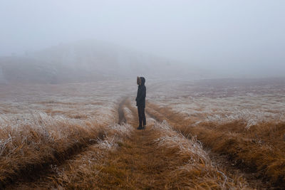Man standing on landscape during foggy weather