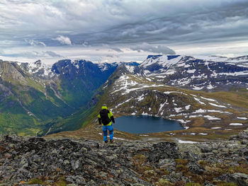 Rear view of hiker on snowcapped mountain against sky