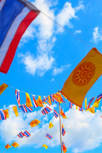 Low angle view of thai flags against sky
