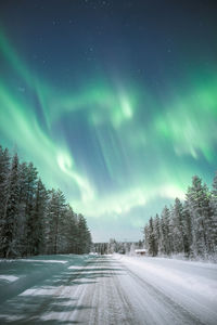 Scenic view of snow covered land against sky during aurora borealis