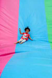 Woman jumping on blue umbrella