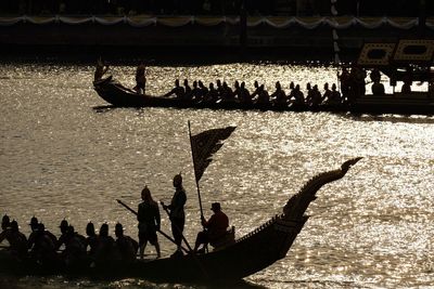 Silhouette people by boats on shore