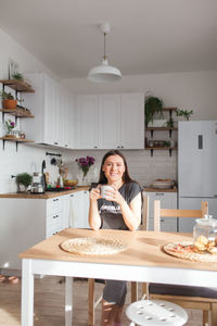 Portrait of woman sitting on table at home