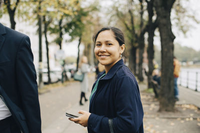 Portrait of confident female entrepreneur with phone standing in city