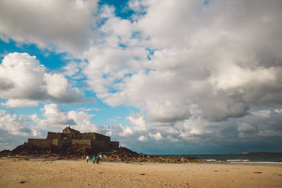 Scenic view of beach against cloudy sky