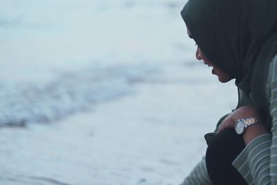 Side view of young woman wearing hijab on shore at beach