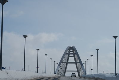 Street lights on bridge against sky during winter