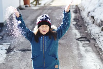 Portrait of smiling girl playing with snow during winter
