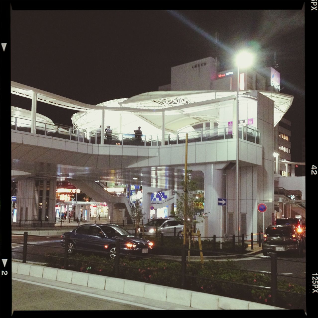 illuminated, architecture, built structure, night, building exterior, transfer print, transportation, city, auto post production filter, street light, city life, lighting equipment, mode of transport, street, incidental people, public transportation, railroad station, sky, railroad station platform, outdoors