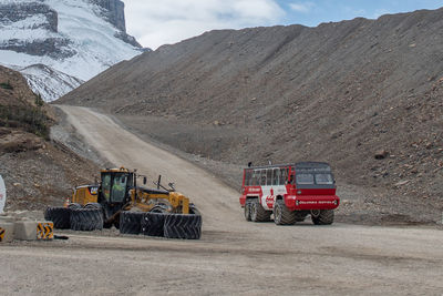 Vehicles on road by land against mountain