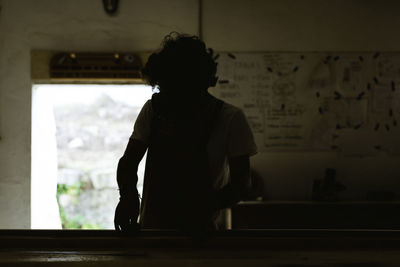 Rear view of silhouette man looking at window