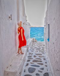 Rear view of woman standing by sea against wall