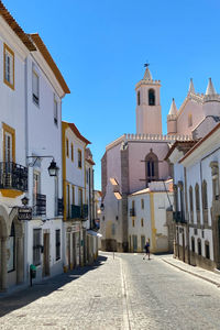 Street amidst buildings in city against clear blue sky