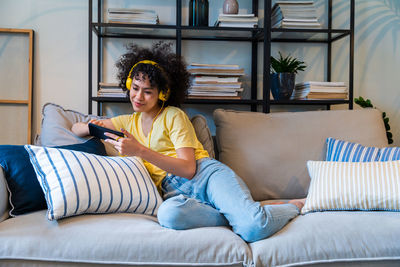 Woman using smart phone sitting on sofa at home