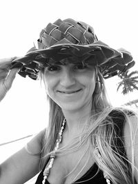 Low angle portrait of smiling woman wearing hat