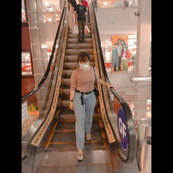 Rear view of people walking on escalator