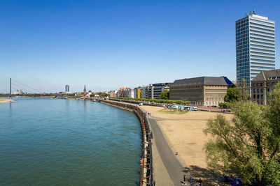 Bridge over river by buildings against clear sky