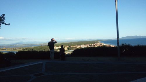 Man photographing on mountain against clear sky