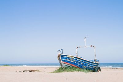Fishing boat on beach against clear sky