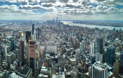 Aerial view of modern buildings in city against cloudy sky