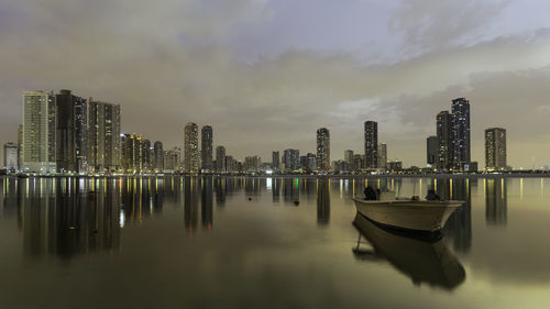 Panoramic view of illuminated city by sea against sky
