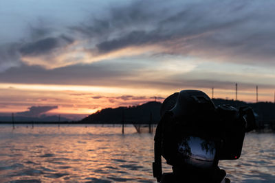 Man photographing sea against sky during sunset