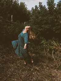 Full length of woman dancing against trees outdoors