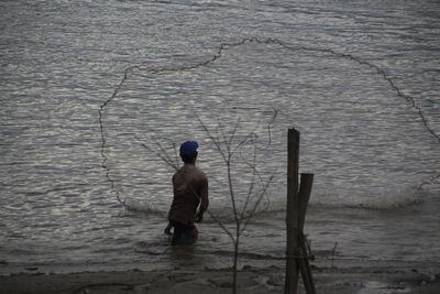 Rear view of man fishing on beach