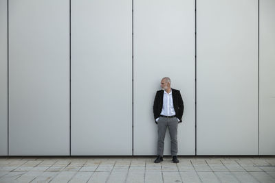 Portrait of adult man in suit against white wall in financial district