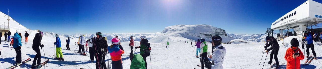 snow, winter, cold temperature, season, blue, clear sky, weather, mountain, panoramic, white color, covering, nature, snowcapped mountain, large group of people, day, sky, beauty in nature, sunlight, frozen, skiing