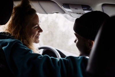 Happy friends looking at each other while talking in car