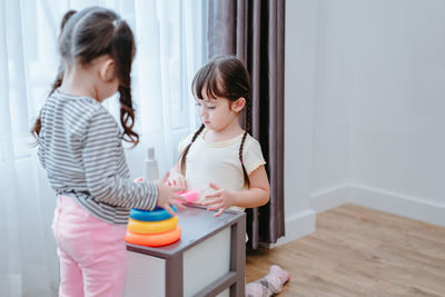 Sisters playing with multi colored toys at home