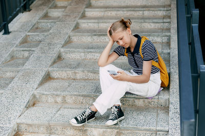 Side view of young woman sitting on steps