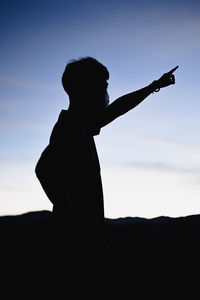 Silhouete young man point his finger to the sky in golden hour