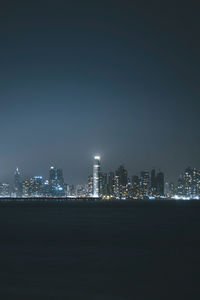 Illuminated buildings in city against clear sky at night