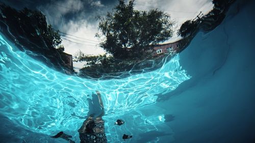 Fish-eye lens of young woman swimming in pool