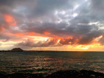 Scenic view of sea against dramatic sky during sunset