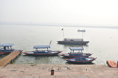 Fishing boats moored in sea against clear sky