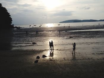 Silhouette people on beach against sky